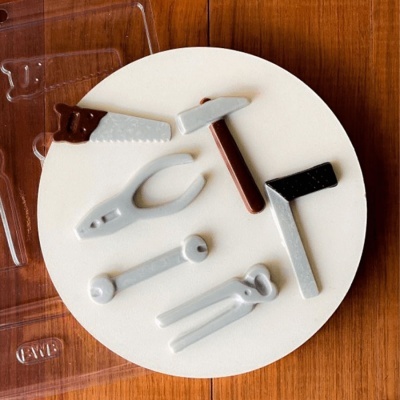 Utensílios de cozinha miniatura de plástico no prato branco sobre mesa de madeira