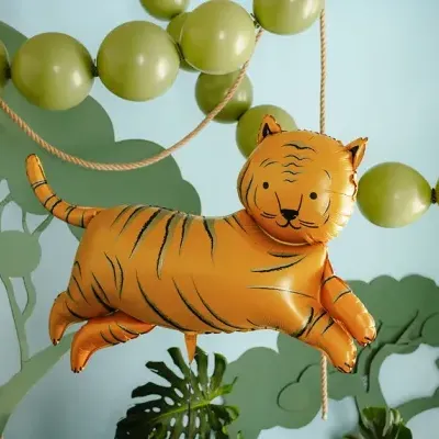 Balão em forma de tigre laranja suspenso com balões e plantas verdes ao fundo