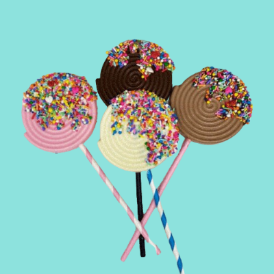 Três pirulitos coloridos com granulados sobre fundo azul claro