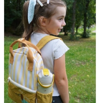 Criança com mochila amarela e branca num parque