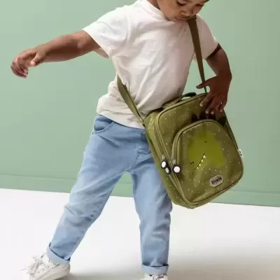 Criança com mochila tiracolo verde com dinossauro