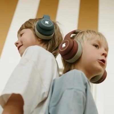 Dois rapazes usam auscultadores grandes sobre a orelha, um azul esverdeado e outro castanho, com logo K branco.