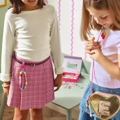 Duas crianças com roupas coloridas e acessórios brincando em ambiente interior