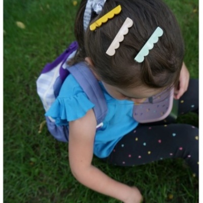 Menina com presilhas coloridas no cabelo sentada na relva