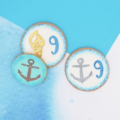 Bolachas decoradas com números e sinal de âncora em fundo azul.