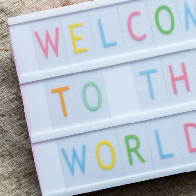 Painel de letras coloridas com a frase 'WELCOME TO THE WORLD'