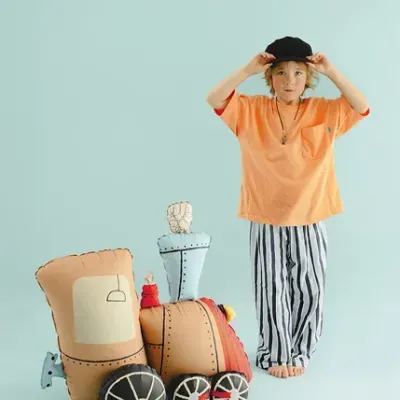 Criança com roupa casual e brinquedo comboio de tecido em fundo azul