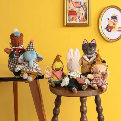 Peluches de animais vestidos sentados em cadeiras de madeira frente a parede amarela com quadros