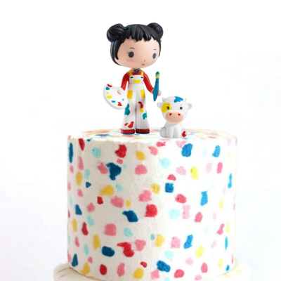 Bolo branco com manchas coloridas e figuras decorativas no topo