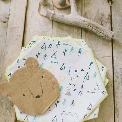 Conjunto de pratos de papel infantil com padrão de natureza e prato pequeno em forma de cabeça de urso castanho, sobre mesa de madeira clara