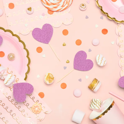 Utensílios de festa cor-de-rosa com decoração de corações e doces