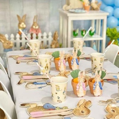 Decoração de mesa para festa infantil com coelhos em papel e enfeites em mini vasos.