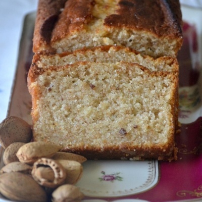 Bolo de noz fatiado com nozes à volta, sobre um tabuleiro decorativo