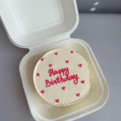 Bolo redondo pequeno com decoração de aniversário em caixa branca aberta