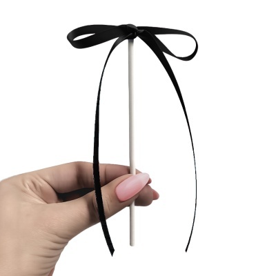 Mão segurando palito branco com laço preto