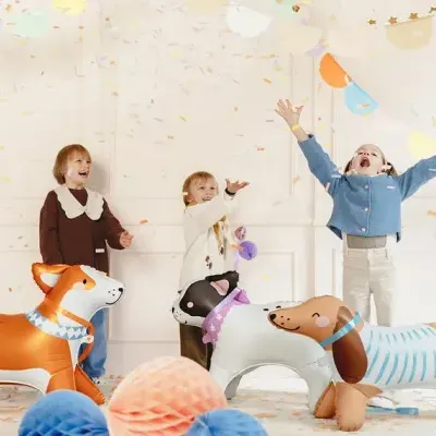 Crianças brincando com balões de ar em forma de cães num ambiente festivo