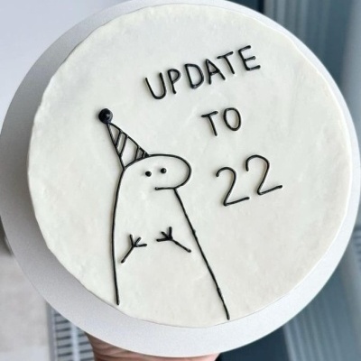 Bolo redondo branco com decoração preta e texto UPDATE TO 22