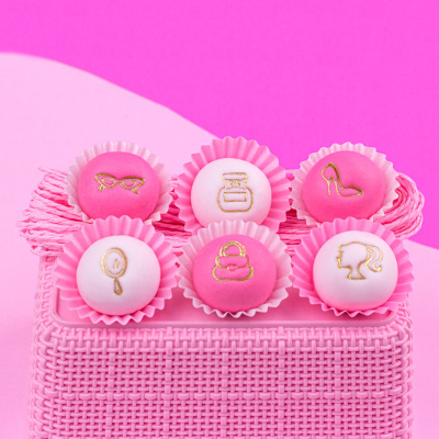Bolinhos decorados rosa e branco com símbolos dourados em cesta rosa
