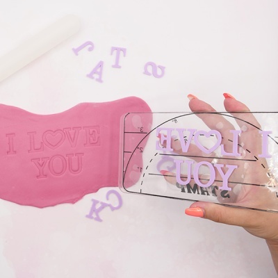 Placa transparente com texto em letras rosa para imprimir massa rosa sobre superfície clara