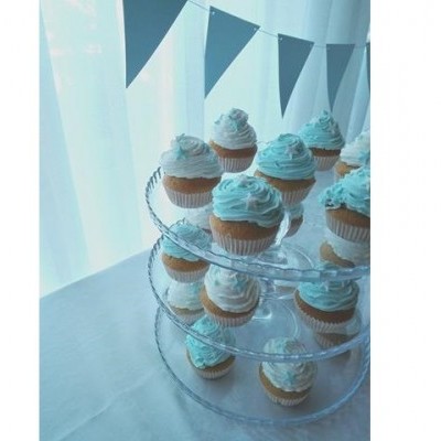 Cupcakes com cobertura azul e branca em suporte transparente de três níveis