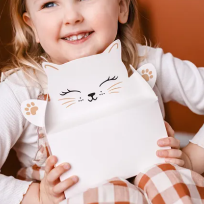 Faixa decorativa branca em forma de gato segurada por criança