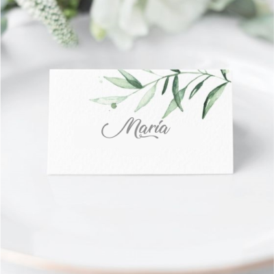 Cartão de nome branco com folhas verdes e nome Maria em caligrafia cinza em prato branco.