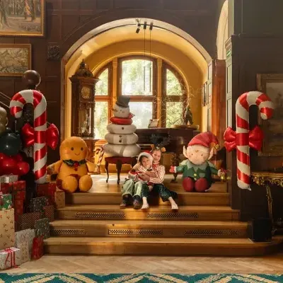 Decoração natalícia com crianças, bonecos decorativos, bengalas doces e presentes num interior clássico