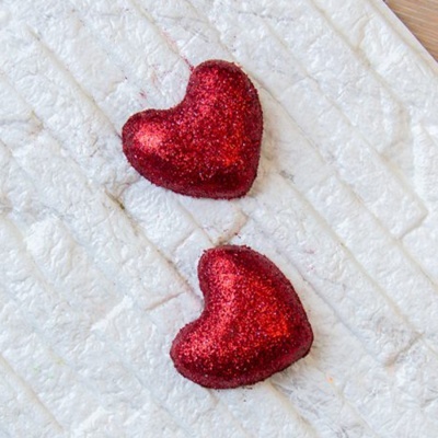 Dois corações vermelhos brilhantes sobre superfície branca texturizada