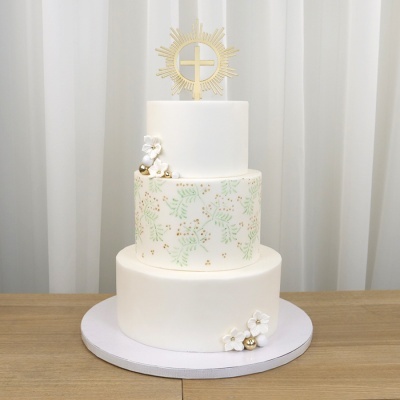 Bolo de três andares decorado com flores brancas e padrão de folhas verdes e douradas