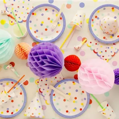 Conjunto de festa colorido com pratos, guardanapos, copos e enfeites de papel com padrão de bolinhas