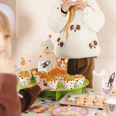 Crianças numa festa infantil com cupcakes e decoração de cães.