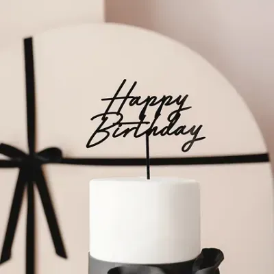 Bolo de aniversário branco com decoração preta e texto Happy Birthday no topo