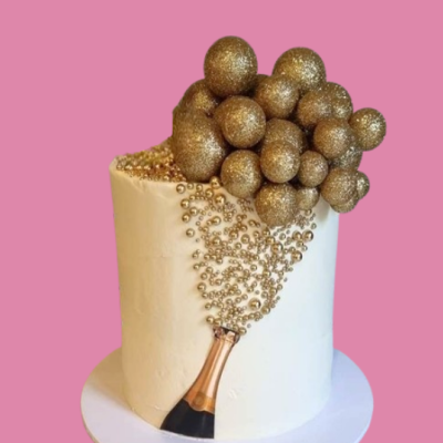 Bolo branco decorado com bolas douradas brilhantes e desenho de garrafa de espumante em fundo rosa