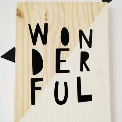 Placa decorativa em madeira com a palavra WONDERFUL escrita em preto