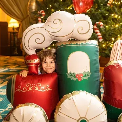 Balão em forma de comboio natalício com criança e árvore de Natal iluminada ao fundo