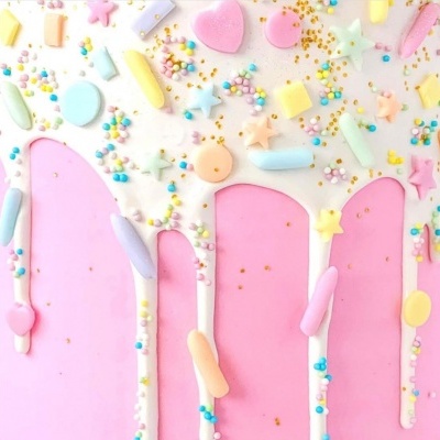 Cobertura branca cremosa com granulados coloridos em fundo rosa