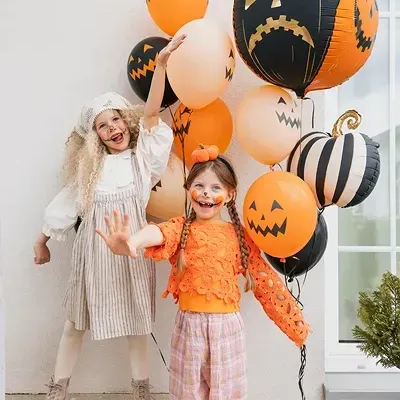 Crianças com balões de Halloween decorados com rostos de abóboras
