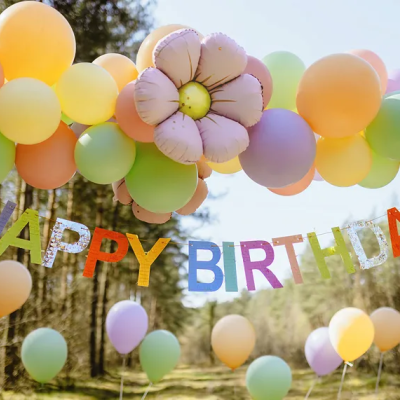 Decoração com balões coloridos pastel e faixa HAPPY BIRTHDAY pendurada em ambiente externo