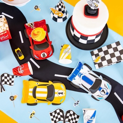 Decoração de festa com carros de corrida, bandeiras xadrez, chapéu temático, copos Rally, cupcakes e pipocas sobre superfície azul e amarela