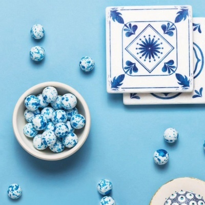 Bolas decorativas brancas com manchas azuis junto a azulejos e fundo azul.