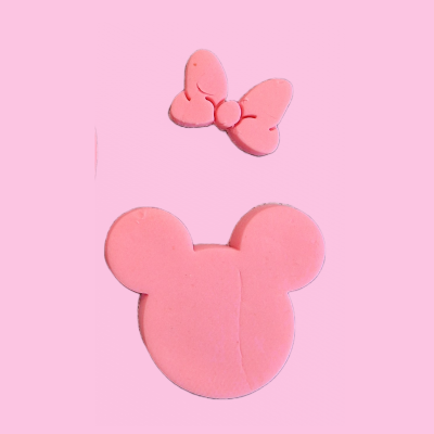 Formas em borracha cor-de-rosa de cabeça de rato e laço sobre fundo cor-de-rosa claro