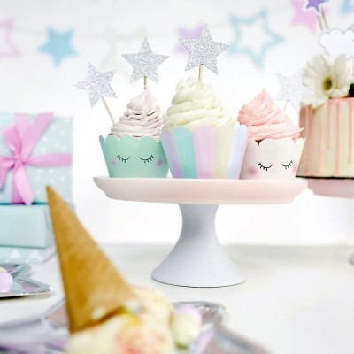 Três cupcakes decorados em suportes coloridos pastel com estrelas prateadas em palitos