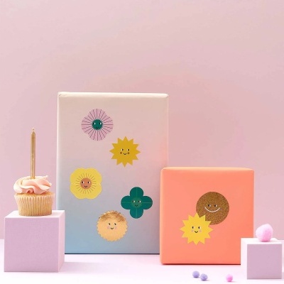Bolo com vela e caixas decoradas em fundo rosa