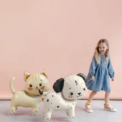 Balões em forma de gato e cachorro com rodas, puxados por criança com vestido azul.