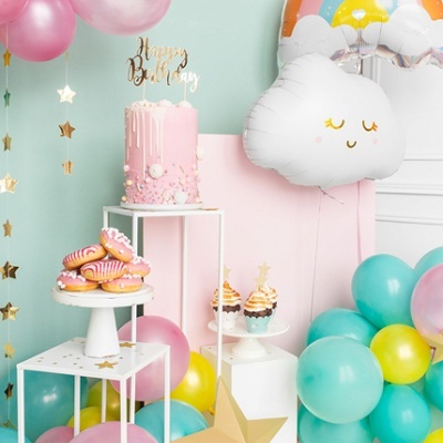 Decoração de festa com balões coloridos, bolo rosa, donuts e cupcakes decorados.