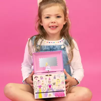 Menina segurando caixa de música rosa com espelho e boneca bailarina