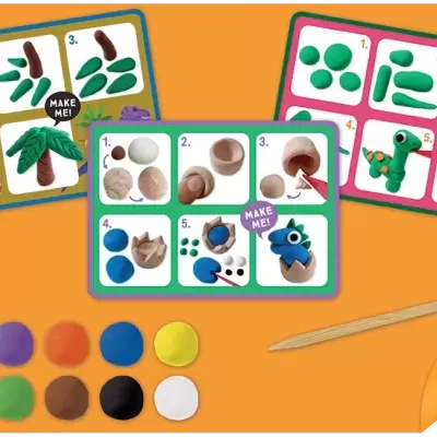 Kit de modelagem com plasticinas coloridas, cartões de instruções e ferramenta de madeira sobre fundo laranja.