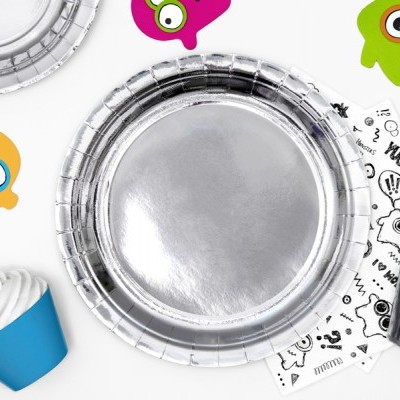 Conjunto de festa com pratos e copos prateados, guardanapos com desenhos, cupcake azul e toppers coloridos