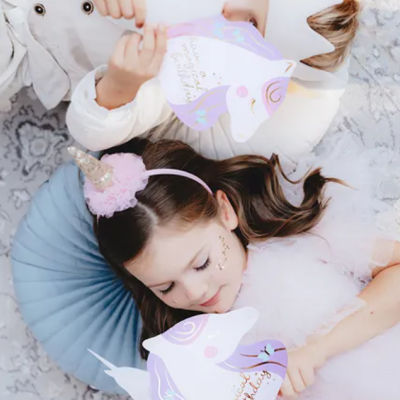 Crianças em festa segurando decorações de unicórnio com texto 'Happy birthday'