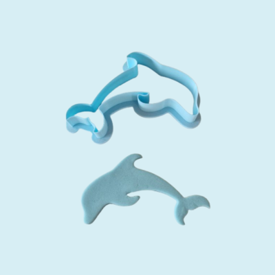 Formador de bolachas em forma de golfinho azul claro com massa azul ao lado